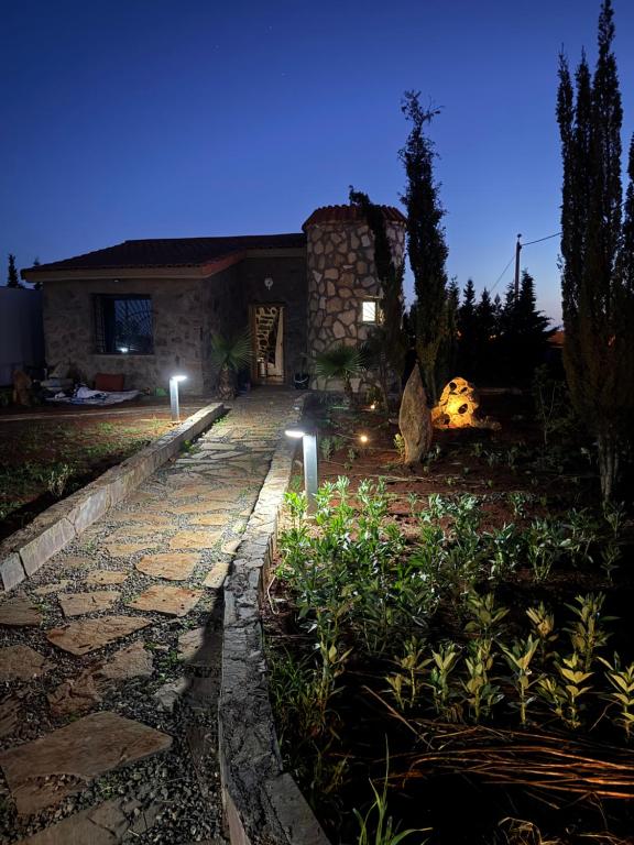 a house with a stone walkway in a yard at night at Chalet en Pierre Benslimane in Aïn Sferjila
