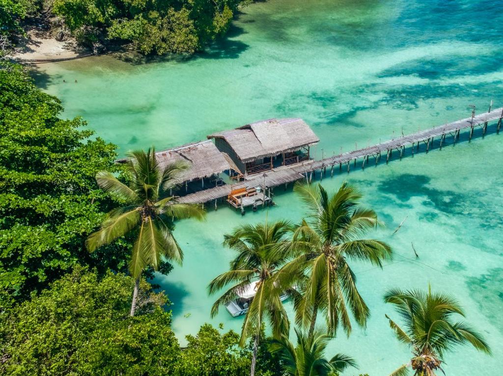 an island with palm trees and a dock in the water at Alter Native Stay in Tapokreng
