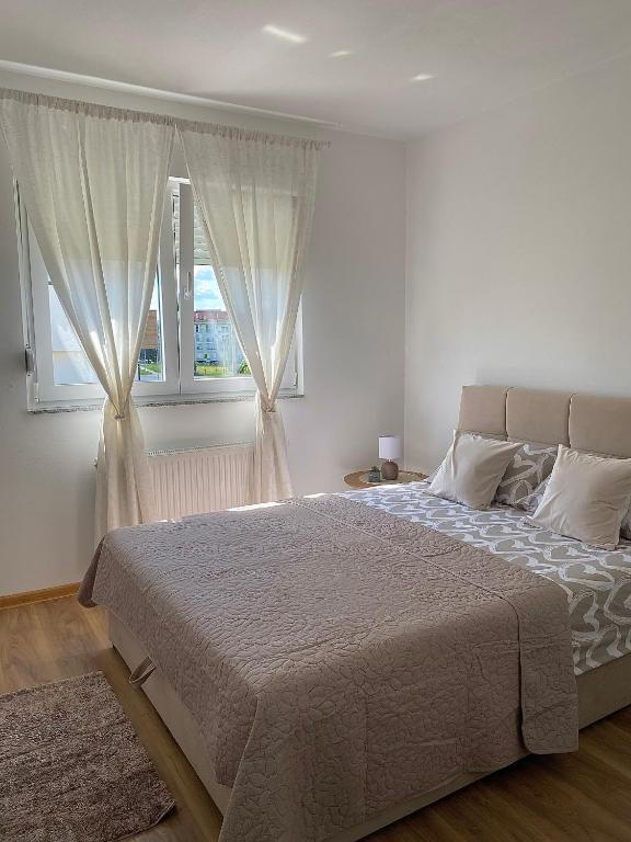 a bedroom with a large bed and two windows at Verde Apartment in Banja Luka