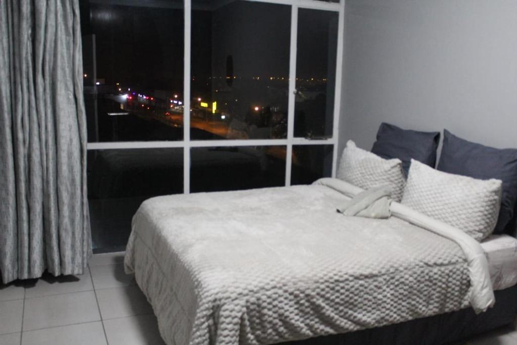 a bedroom with a bed and a large window at Penthouse in Bloemfontein