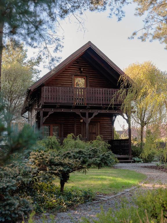 a log cabin with a porch and a balcony at Domek Hortensja in Zawady