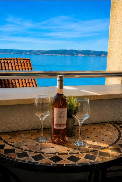 a bottle of wine on a table with two wine glasses at Apartments MB in Kaštela