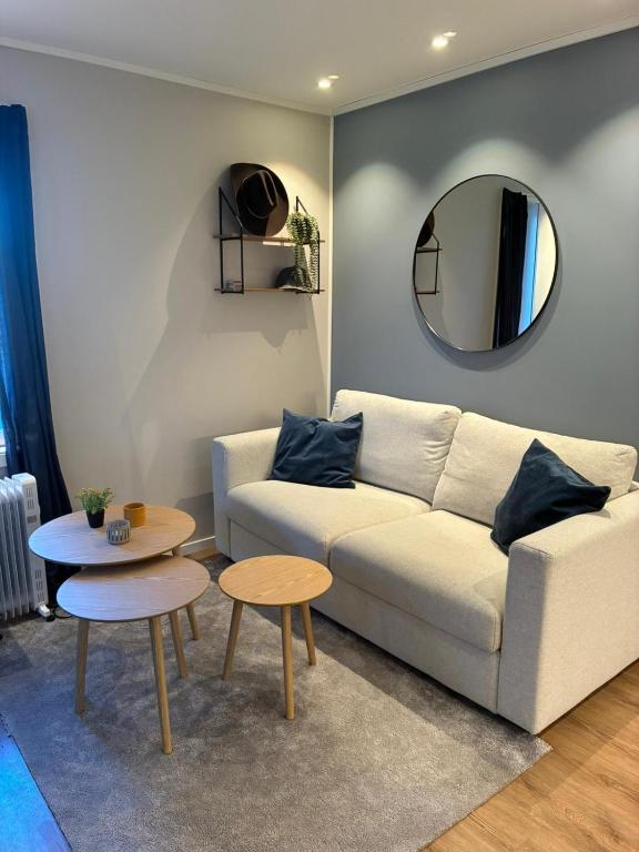 a living room with a white couch and a mirror at Nyoppusset hybelleilighet in Bjørkheim