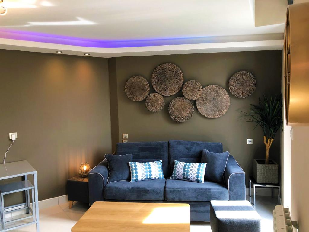 a living room with a blue couch and wooden plates on the wall at Le centre in Montluçon
