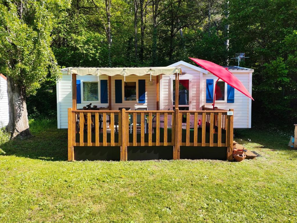 a small house with a porch and an umbrella at MOBIL-HOME n 95 in Barrême