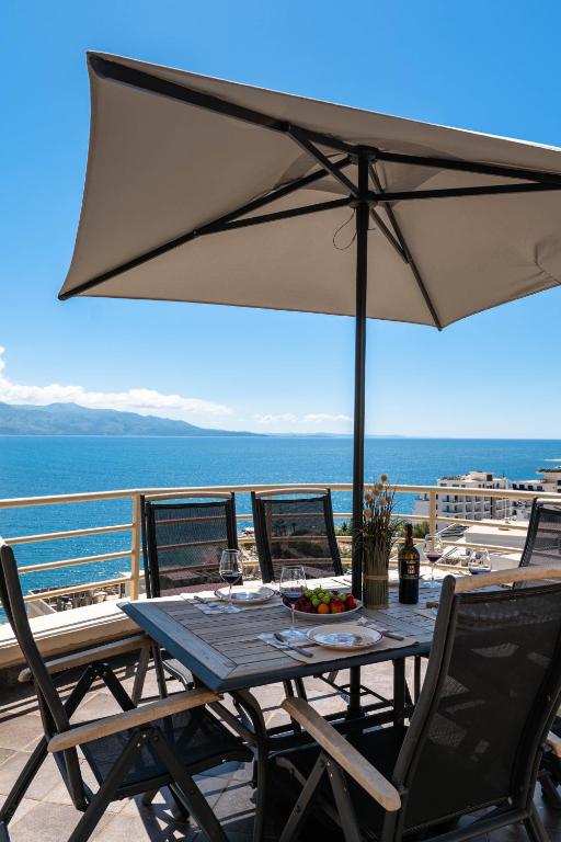 a table and chairs with an umbrella on a balcony at ERAL Apart-Hotel & Penthouse in Sarandë