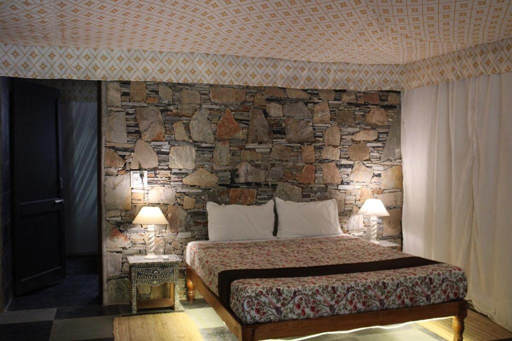 a bedroom with a stone wall with a bed and two lamps at The chocolate frog in Thūr
