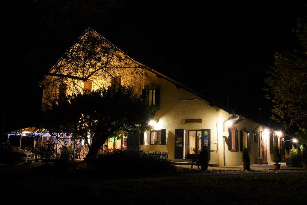 a building at night with a tree in front of it at Glamping at Camping La Source in Saint-Pierre-dʼArgençon