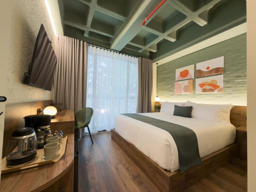 a bedroom with a bed and a desk and a window at Urbit Garden Hotel in Medellín