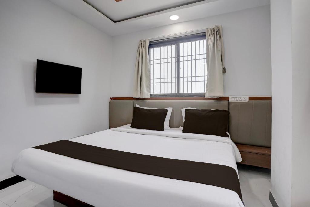 a bedroom with a large bed and a window at Hotel O Shree Lodging in Aurangabad