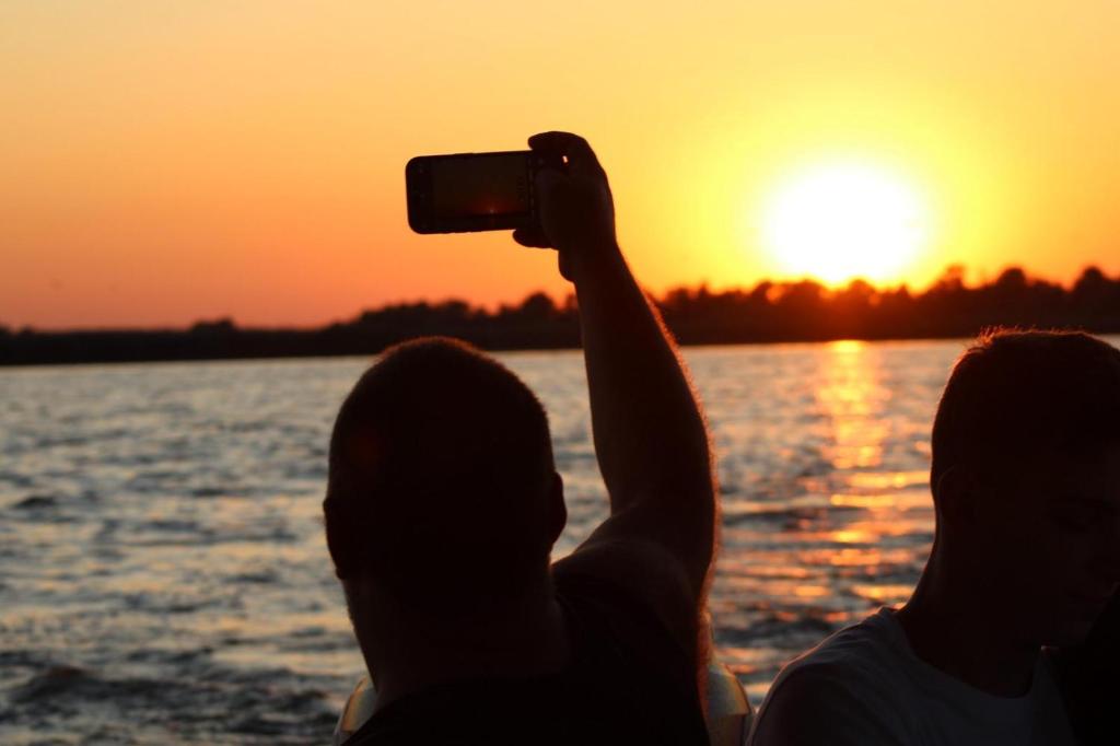 two people taking a picture of the sunset on a boat at Murighiol Excursii in Murighiol