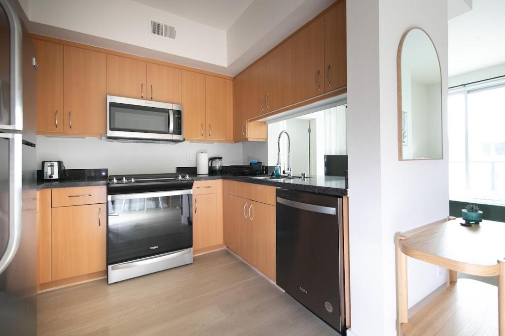 a kitchen with wooden cabinets and black appliances at Central Penthouse Studio with Free Parking in Los Angeles