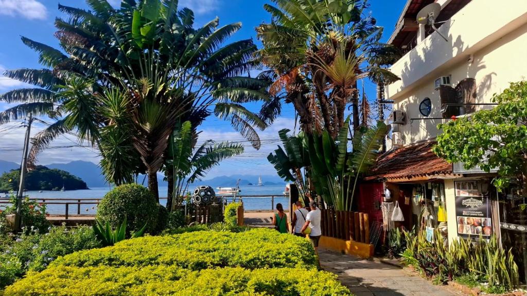 a street in front of a building with palm trees at Bouganvile Hostel Ilha Grande in Abraão