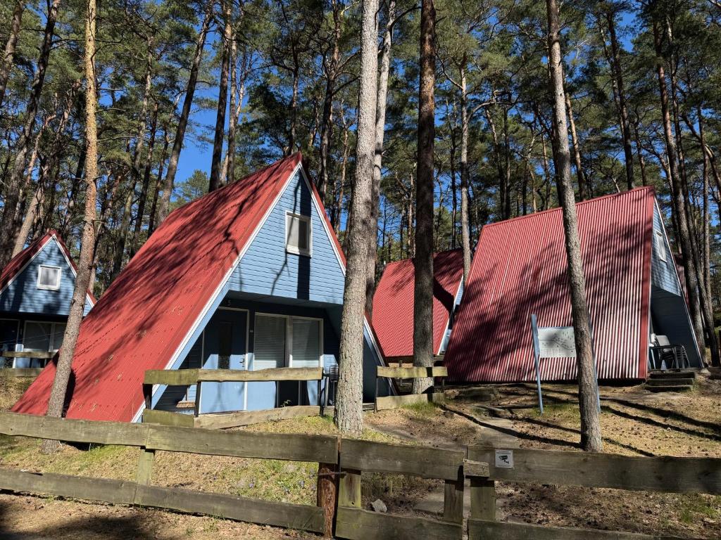 two houses with red roofs in the woods at Abseits vom Alltag, Finnhütte umgeben von Wald und frischer Luft - Fiete in Trassenheide