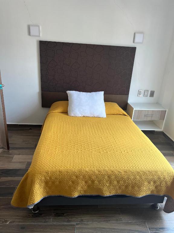 a bedroom with a yellow bed with a pillow on it at Hotel Angeles in Ciudad Serdán