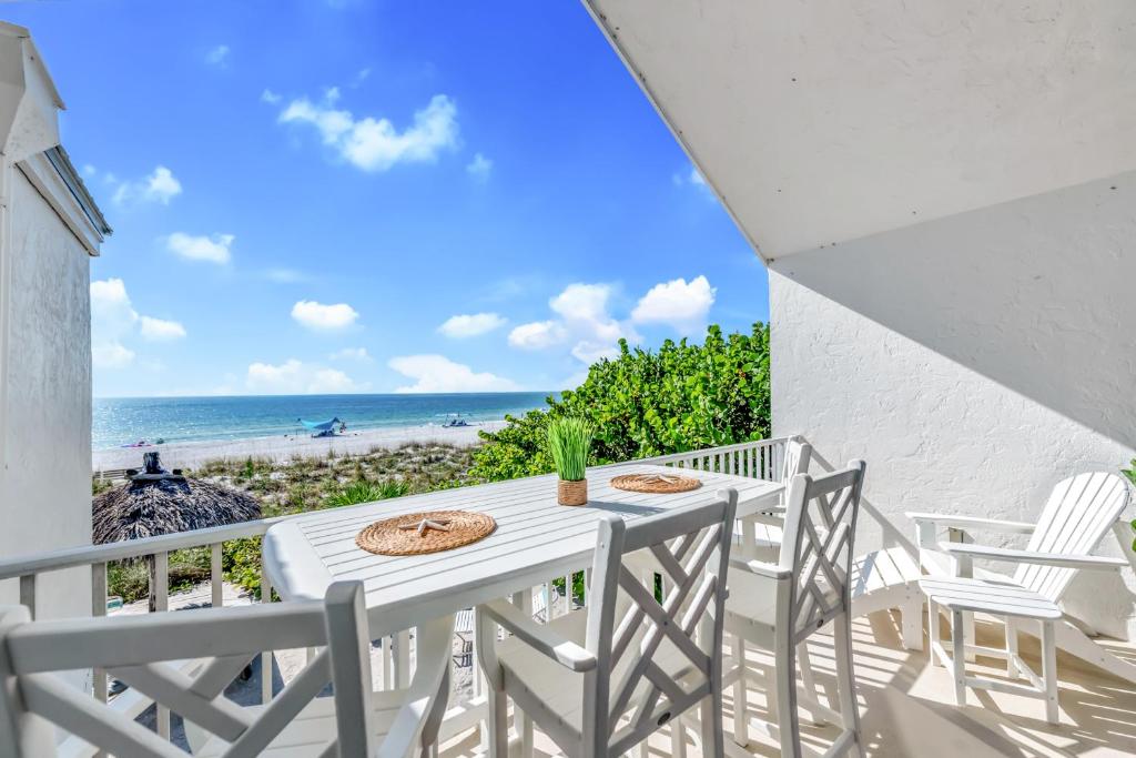 a white table and chairs on a balcony with the beach at Coconuts Beachfront #112 in Holmes Beach
