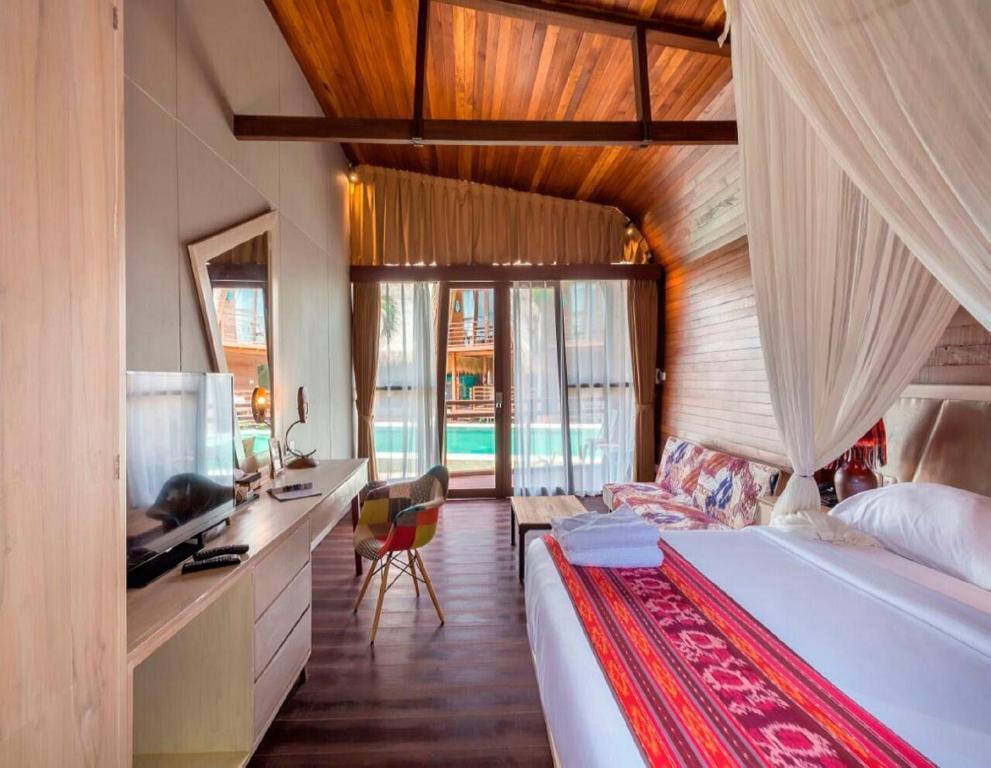 a bedroom with a bed and a desk and a television at Mola2 Resort Gili Air in Gili Islands