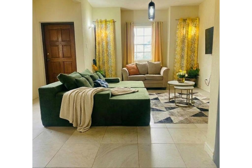a living room with a green couch and a chair at Casa Amarilla St Michael in Bridgetown