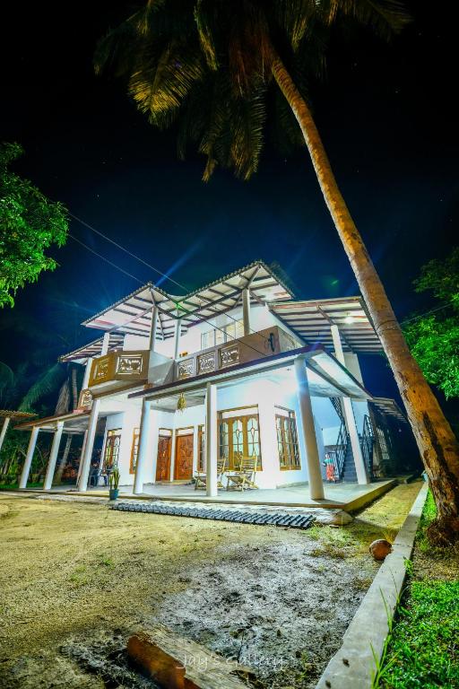a building with a palm tree in front of it at Nandana Homestay in Udawalawe