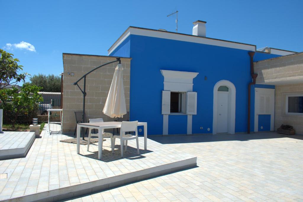 a blue building with a table and an umbrella at Kasamare- Monopoli in Monopoli
