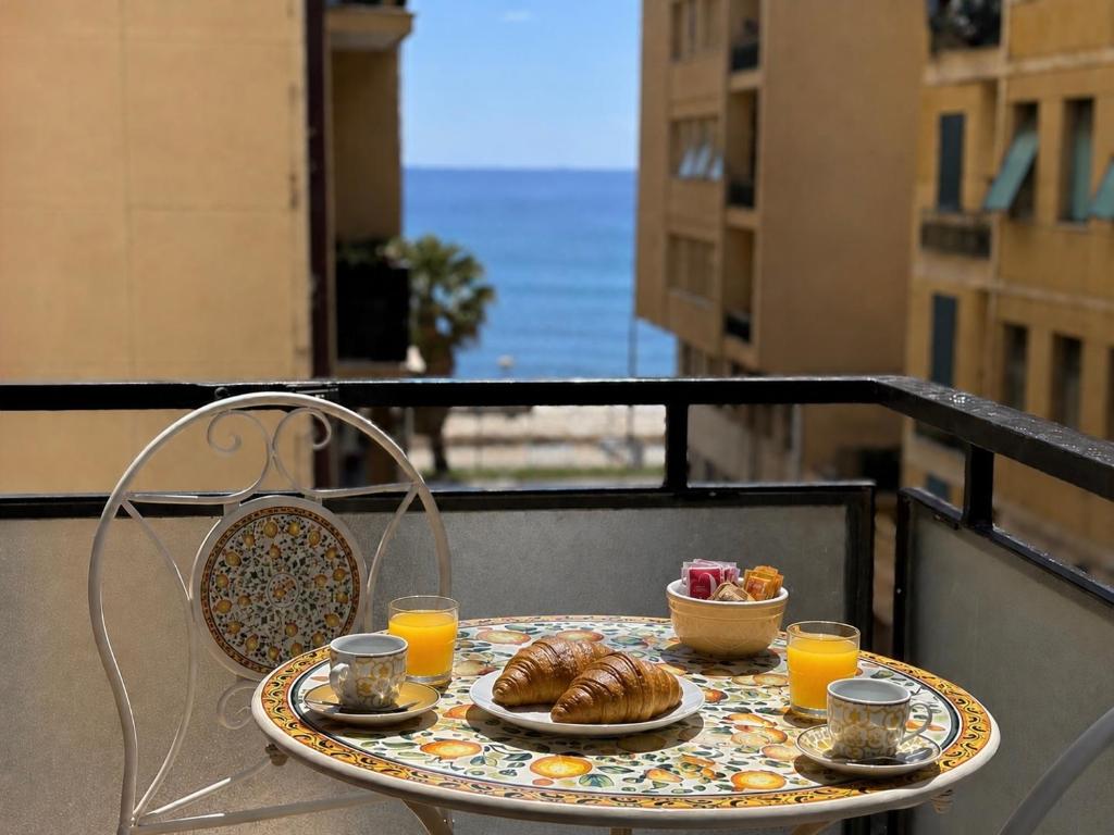 a table with a breakfast of croissants and orange juice at Sea View Apartment - Private Parking AC in Savona