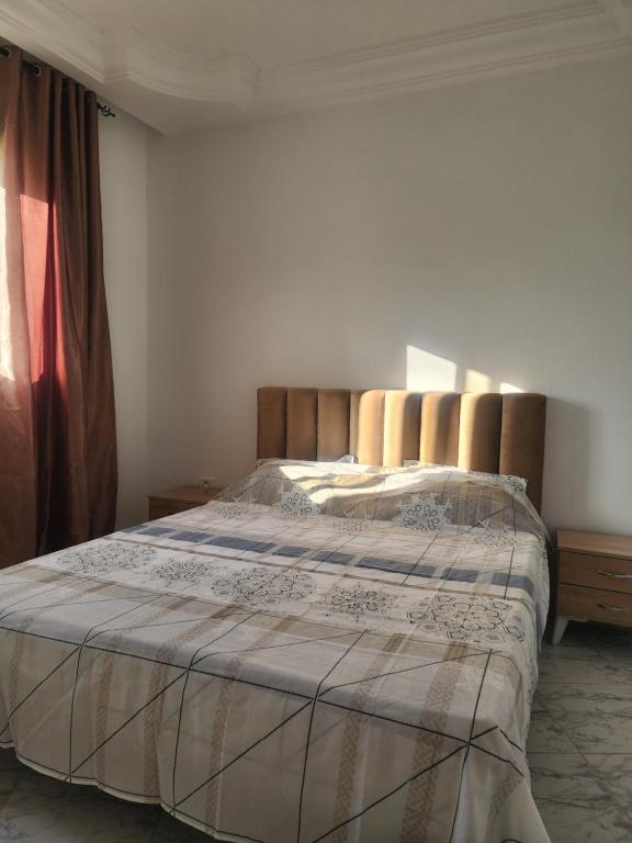 a bedroom with a large bed with a wooden headboard at F3 entre nature et calme in Raʼs al Jabal
