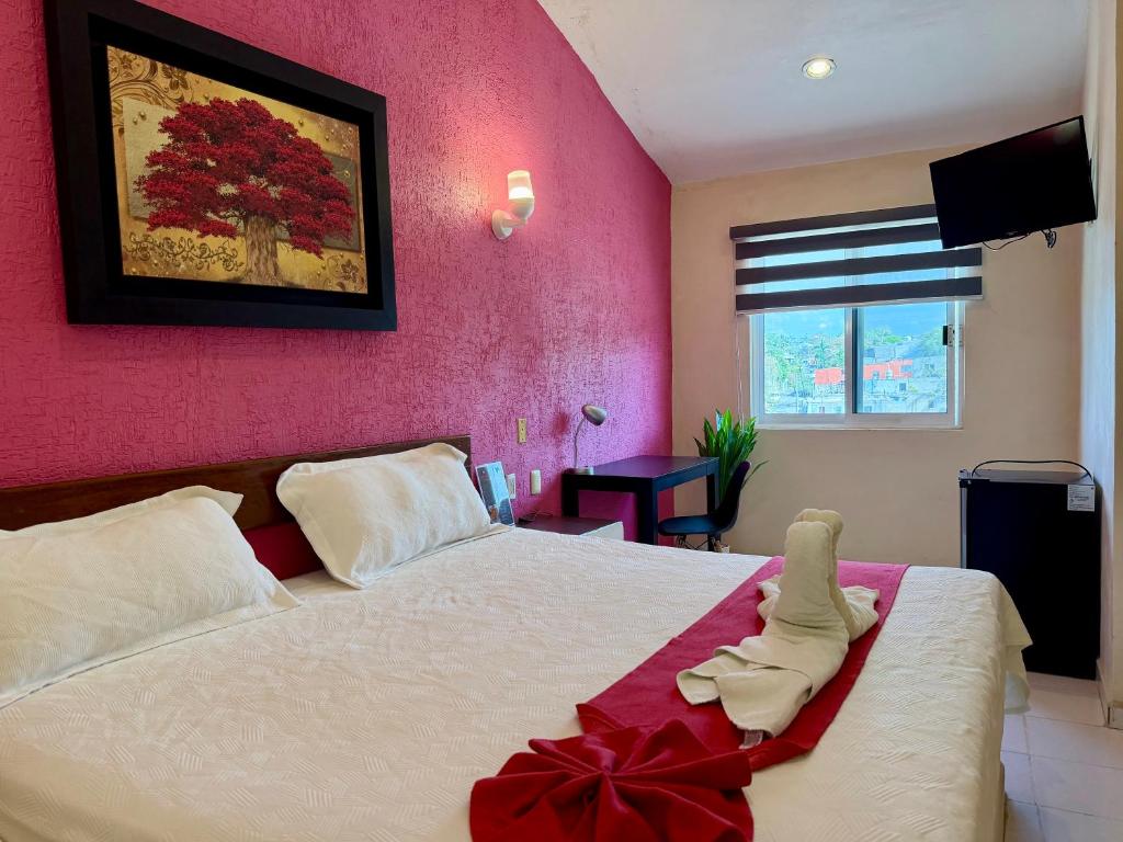 a bedroom with a white bed with a red bow on it at Hotel Barranquilla in Campeche