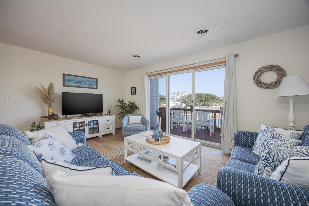 a living room with blue and white furniture and a television at 4203 - Here Comes the Sun in Duck
