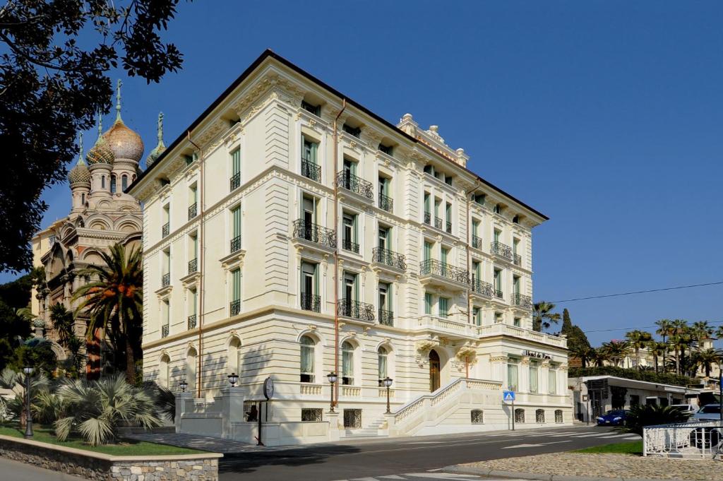 un grand bâtiment blanc avec une tour dans l'établissement Hotel De Paris Sanremo, à Sanremo