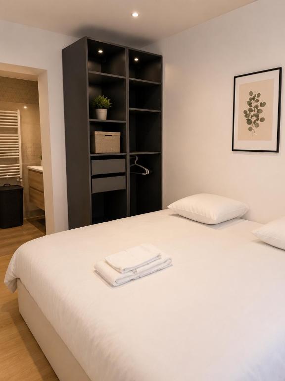 a bedroom with a white bed and a black book shelf at LE 23 ter in Jarny