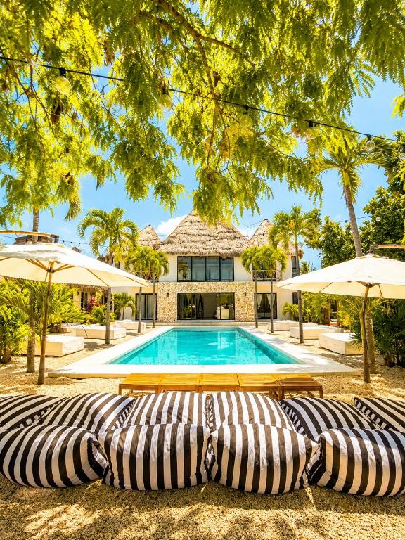a swimming pool with two lounge chairs and umbrellas at Villa Luxauthentika Tulum in Tulum