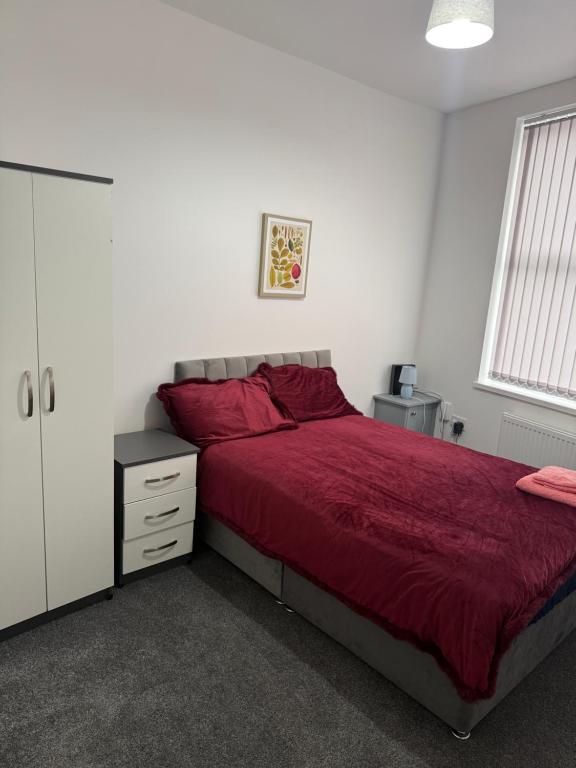 ein Schlafzimmer mit einem Bett mit roter Tagesdecke in der Unterkunft PLUS Properties Dike 1 in Stoke on Trent