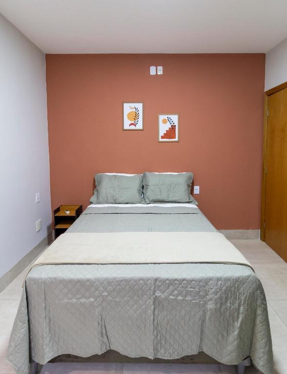 a large bed in a bedroom with orange walls at MOOVE Stay - Suite Cacau no centro in Uberlândia