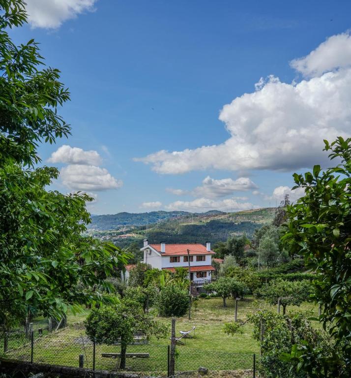 a house in the middle of a field with trees at Casa da Pedrada in Ponte da Barca