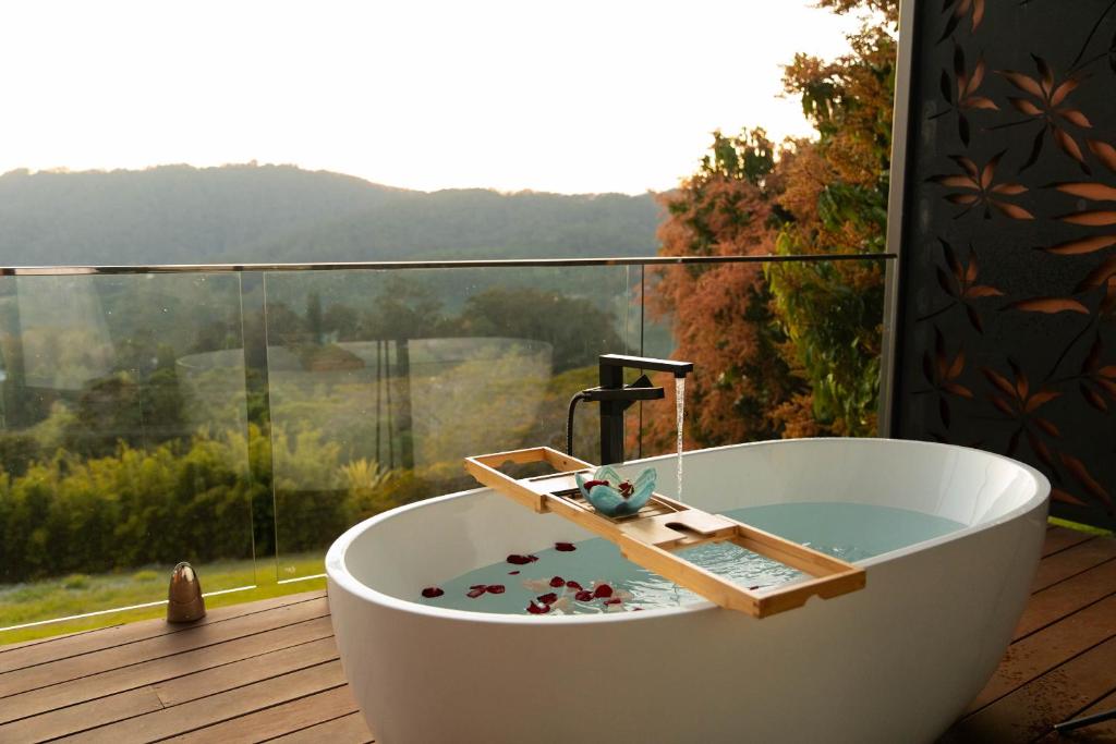 a white bath tub sitting on a deck with a window at On Eagle Wings Mountain Retreat & Spa in Neranwood