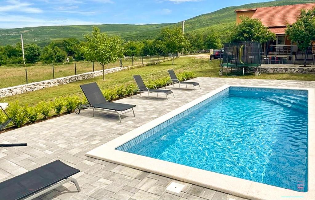 a large swimming pool with chairs and a house at Stunning Home In Sinj in Sinj
