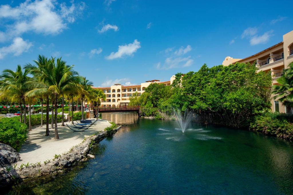 a body of water with palm trees and buildings at Kimpton Tres Rios - All Inclusive in Playa del Carmen