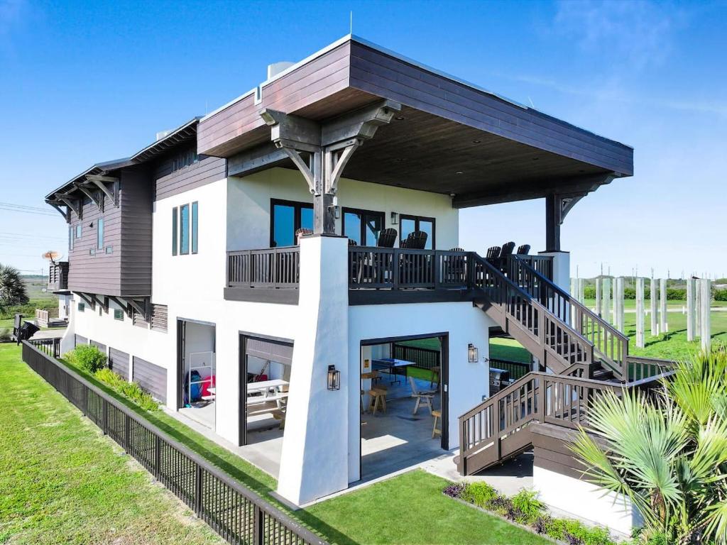 a house with a wrap around porch with a deck at Luxury Beachfront Ocean Views Pool Access Sleeps15 in Bolivar Peninsula