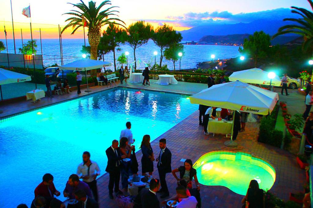 a group of people standing around a swimming pool at Turas Club Case Vacanze in Bosa