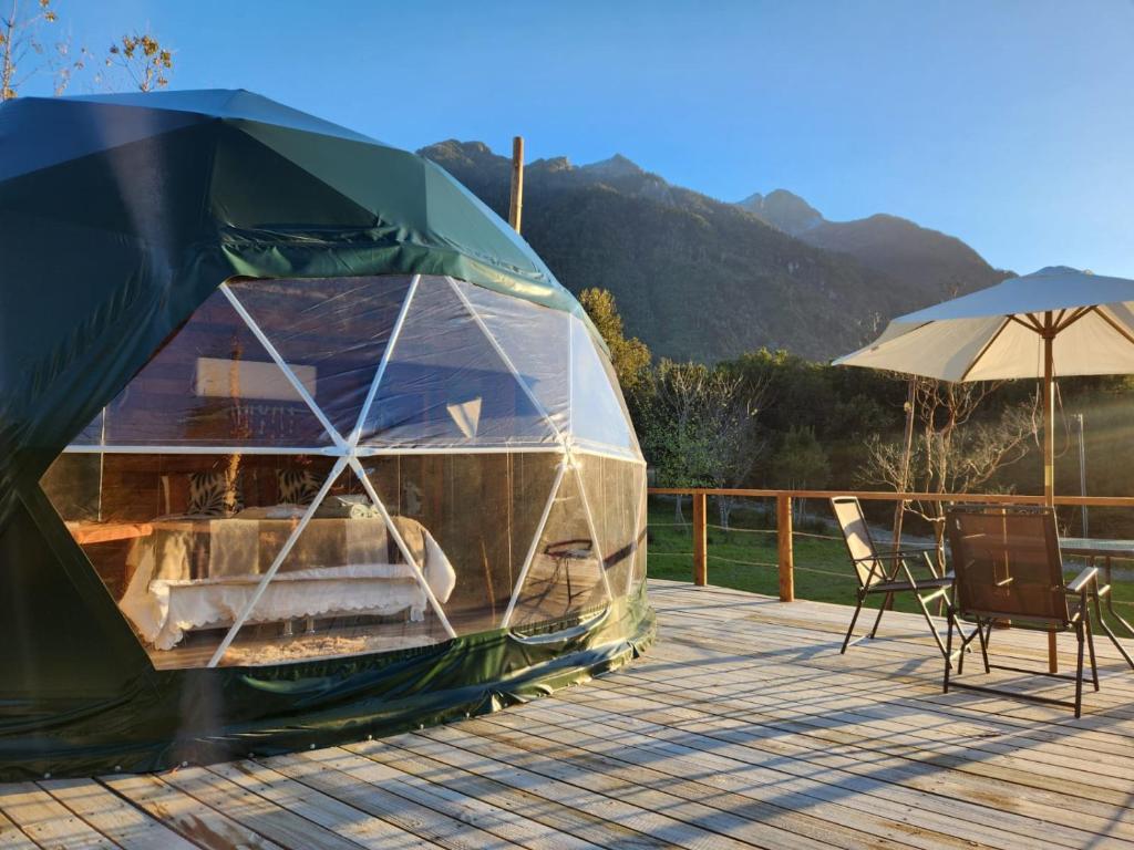 a tent on a deck with a chair and an umbrella at Alma Lemu Lodge in Los Ladrillos