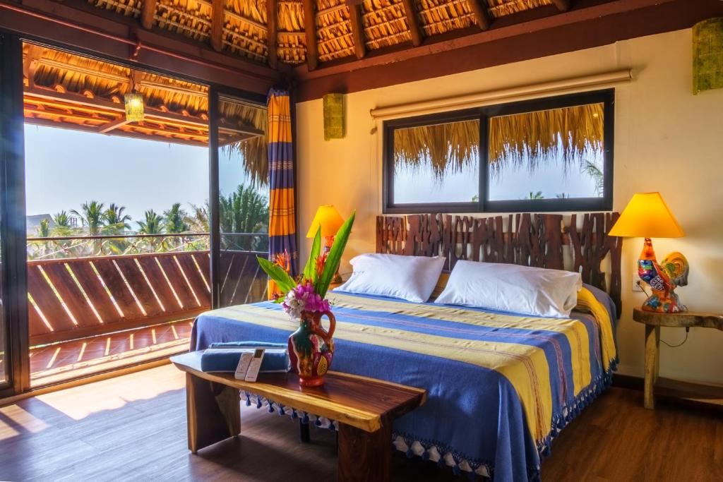 a bedroom with a bed and a table and windows at Hotel Casamar Suites in Puerto Escondido