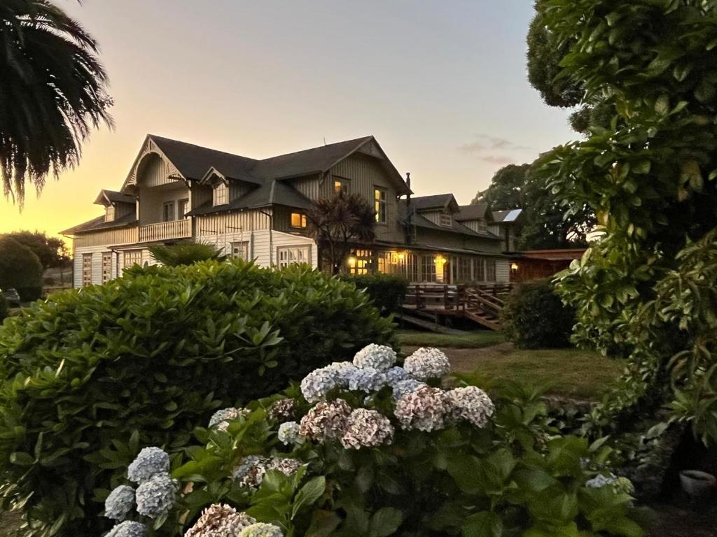 a large white house with flowers in front of it at Playa Maqui Lodge in Frutillar