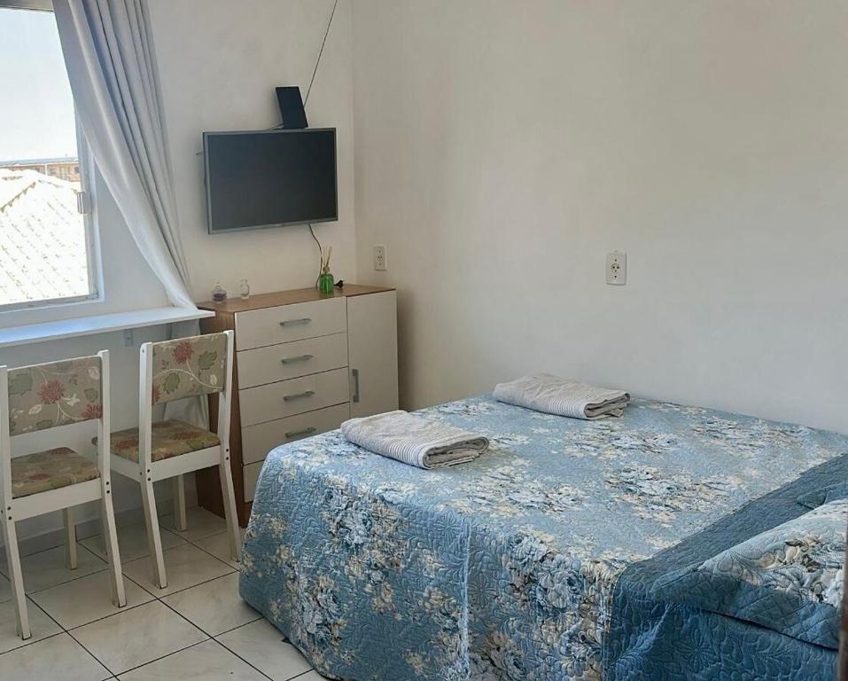 a bedroom with a bed and a chair and a tv at Loft Pedra Branca - Unisul in Palhoça