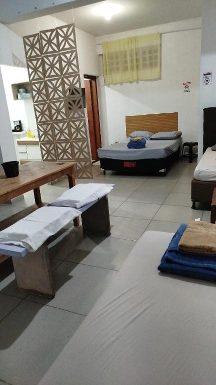 a room with two beds and a table and benches at Studio Apto Central próximo a Orla in Fatima do Sul
