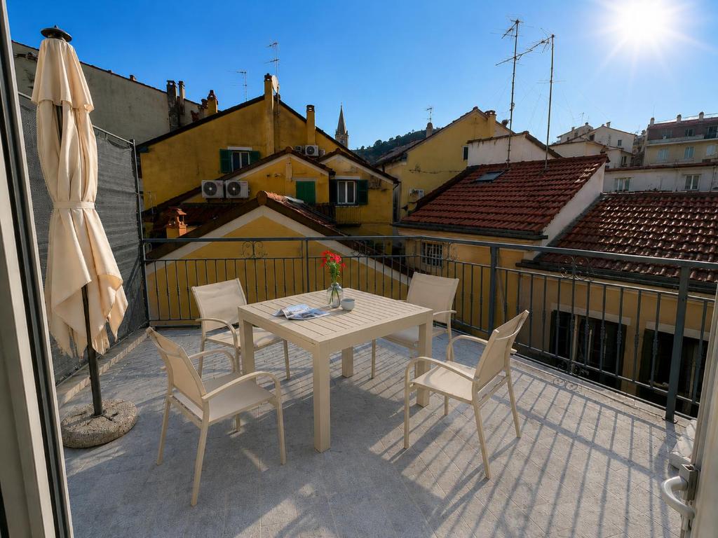 a patio with a table and chairs on a balcony at Alassio Attico con Terrazza AC WIFI in Alassio