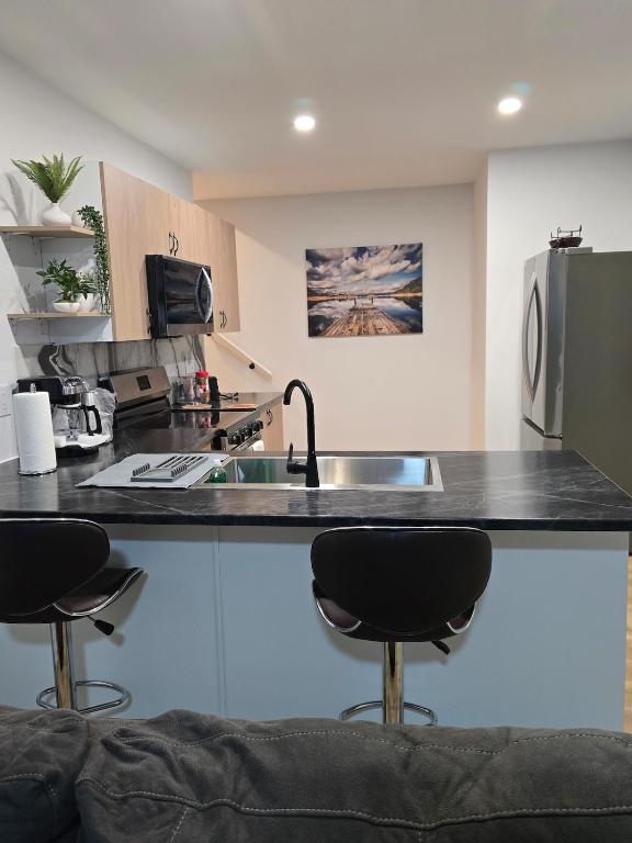 a kitchen with a counter and two bar stools at Serene luxury apartment in Moncton