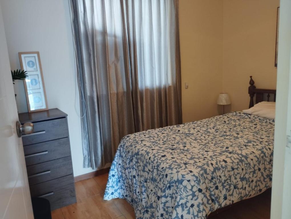a bedroom with a bed and a dresser and a window at Casa en condominio in Moche
