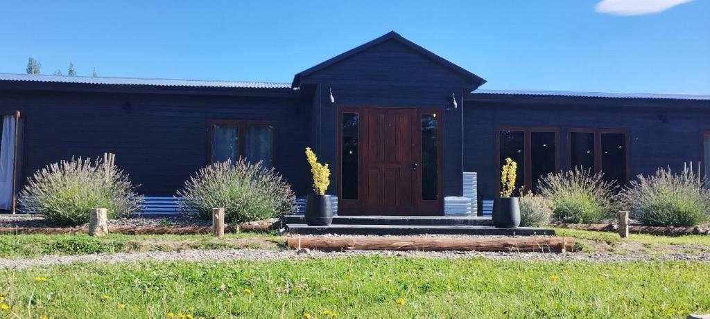 a black house with a wooden door in a yard at Hostería Ayres del Lago in Los Antiguos