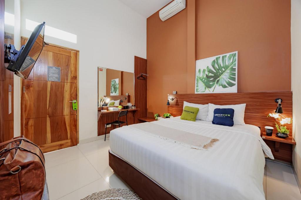 a bedroom with a large white bed and a television at Urbanview Darmo Residence Bandung in Bandung