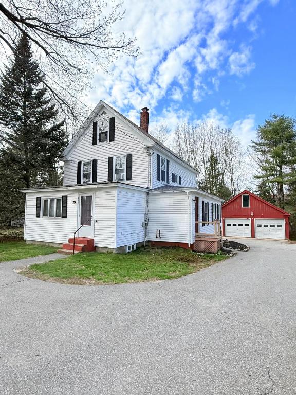 a white house with a red barn in front of it at The Saco Valley Stay in Conway